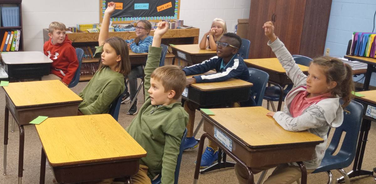 Students with raised hands in classroom
